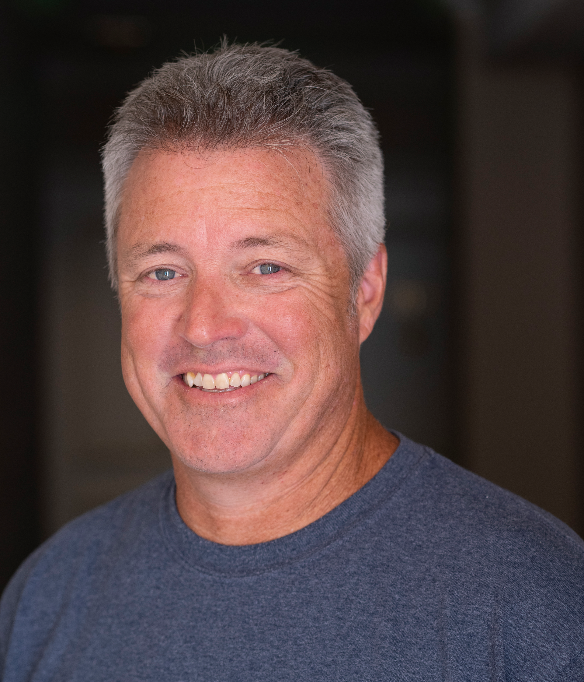A man with gray hair and a blue shirt.